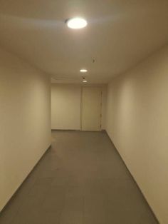 an empty hallway with white walls and light fixtures on the ceiling is lit by recessed lights