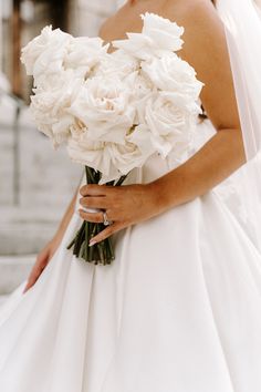 a bride holding a bouquet of white flowers