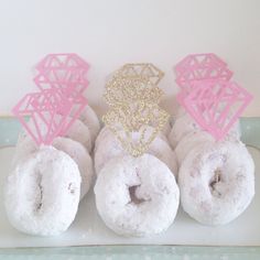 there are donuts with pink frosting and gold decorations on the top each one