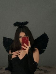 a woman taking a selfie in front of her mirror with angel wings on her head