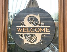 a welcome sign hanging from the side of a wooden door