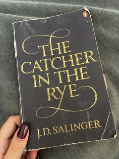 a person holding up a book in their hand with the title'the catcher in the rye '