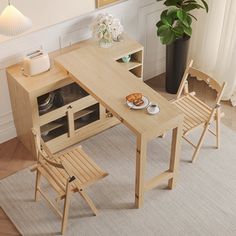 a wooden table with two chairs next to it and a potted plant in the corner