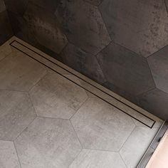 the corner of a bathroom with tile flooring and walls in grey tones, including hexagonal tiles