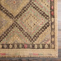 an old rug is laying on the floor with wood floors in the background and a wooden wall behind it