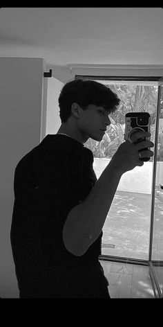 a young man taking a photo with his cell phone in front of a glass door