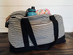 a black and white striped duffel bag with a bottle in it on a wooden table