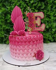 a pink cake decorated with flowers and the letter b