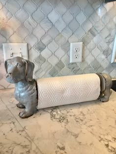 a dog figurine sitting on top of a counter next to a roll of toilet paper