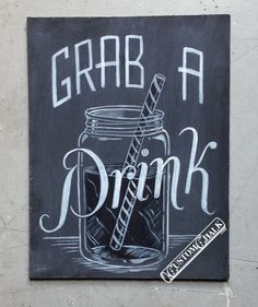 a chalkboard sign on the side of a building that says grab a drink with a straw