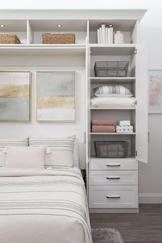 a bedroom with white furniture and linens on the shelves above the bed is shown