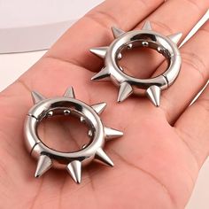 pair of silver spike stud earrings in palm with white background and person holding out their hand