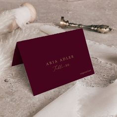 a red business card sitting on top of a table next to a bottle of wine