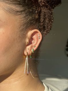 a close up of a person's ear wearing some kind of earring with green and white stones