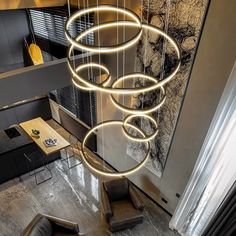 a modern chandelier hanging from the ceiling above a living room table and chairs