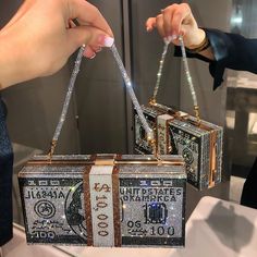 two women are holding purses made out of dollar bills and diamonds on display at an event