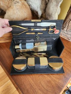 an open leather case with various grooming items in it on a wooden table next to a stuffed animal