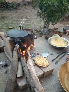 two people are cooking food over an open fire