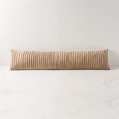 a beige decorative pillow on a white table with marble flooring and walls in the background