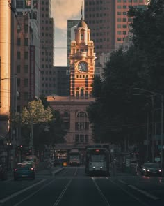 a bus driving down a street in front of tall buildings with a clock on it