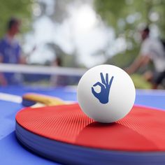 a ping pong table with a white ball on it and a paddle in the foreground