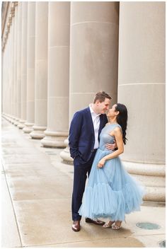 a man and woman standing next to each other in front of some tall pillars with columns