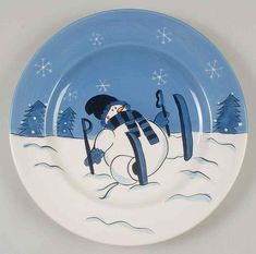 a blue and white plate with a snowman holding skis in it's mouth