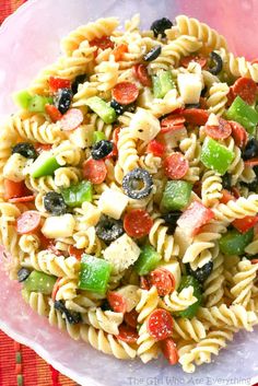 a bowl filled with pasta salad on top of a red place mat next to a fork