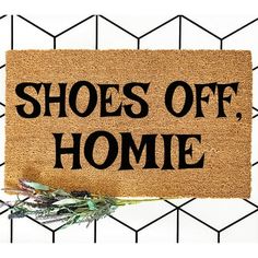 a door mat that says shoes off, home on it with a plant next to it