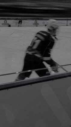 a man skating on an ice rink with his reflection in the glass window behind him