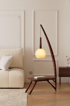 a white couch sitting next to a wooden table and lamp in a living room on top of a hard wood floor