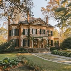 a large brick house sitting in the middle of a lush green field with lots of trees