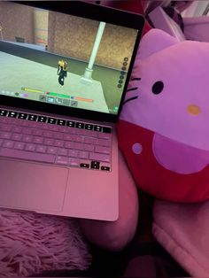 a laptop computer sitting on top of a pink couch next to a stuffed animal cat