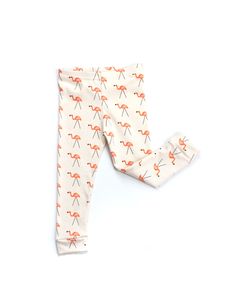 a baby's leggings with an orange flamingos pattern on it, sitting next to a white background