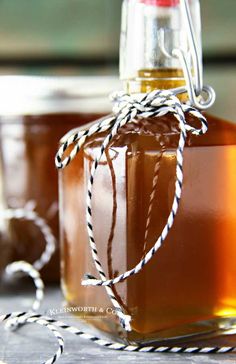 two jars filled with liquid sitting on top of a wooden table next to twined twine