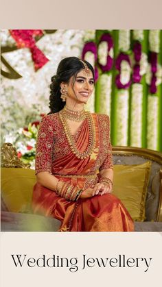 a woman sitting on top of a couch wearing a red and gold sari dress