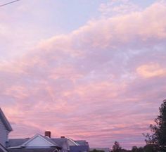 the sky is pink and blue as the sun goes down over houses in this neighborhood