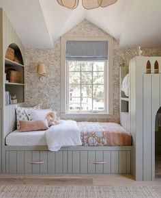 a room with a bed, window and shelves in the corner that are built into the wall