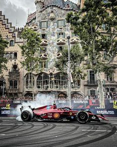 a red race car driving past a tall building