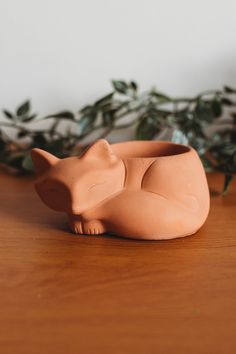 a clay cat planter sitting on top of a wooden table