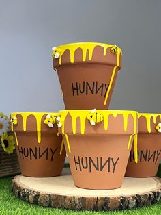 four flower pots sitting on top of a tree stump covered in yellow paint with the words hummy painted on them