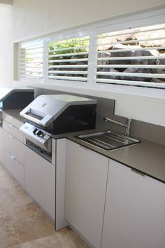 a kitchen counter with a printer on top of it next to a sink and window