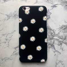 a black phone case with white daisies on it sitting on a marble countertop