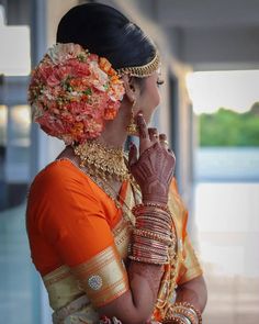 a woman in an orange and gold outfit with flowers on her head