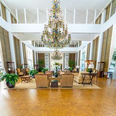 a large living room filled with furniture and a chandelier hanging from the ceiling