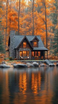 a log cabin sits on the shore of a lake surrounded by trees with orange leaves