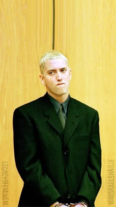 a man in a suit and tie sitting on a chair with his hands folded out