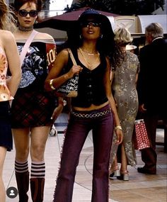 two women are walking down the street in high heeled boots and tights, one is holding an umbrella