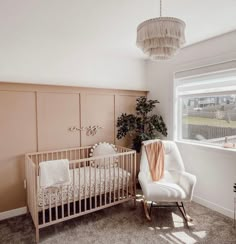 a baby's room with a crib, rocking chair and potted plant