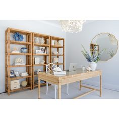 a room with a desk, mirror and shelves filled with vases on top of it